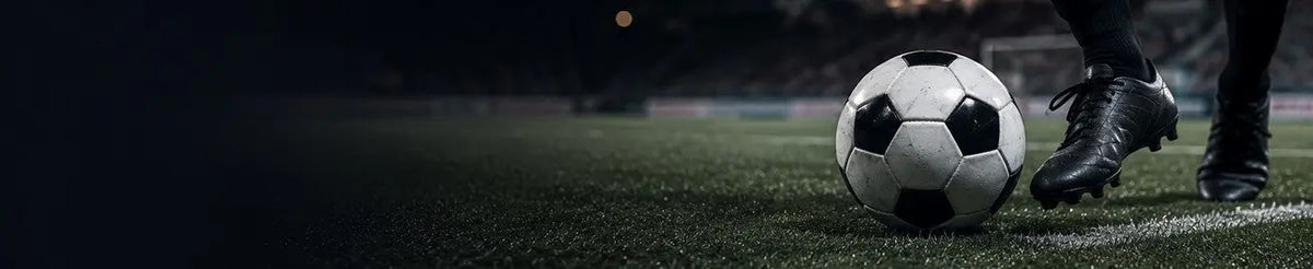 Fotboll vid spelares fötter på en mörk fotbollsplan