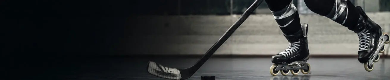Inlinehockeyspelare med klubba och rullskridskor på mörk rink.