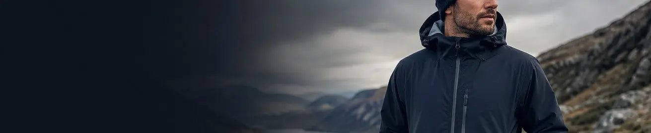 Man i mörk jacka i ett kargt bergslandskap